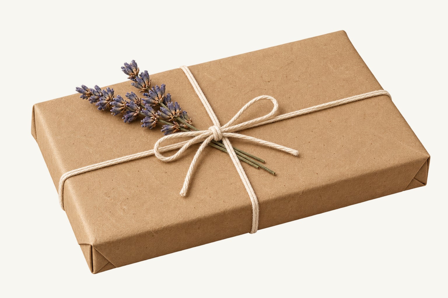 A flat gift wrapped in kraft paper and tied with twine and a lavender sprig