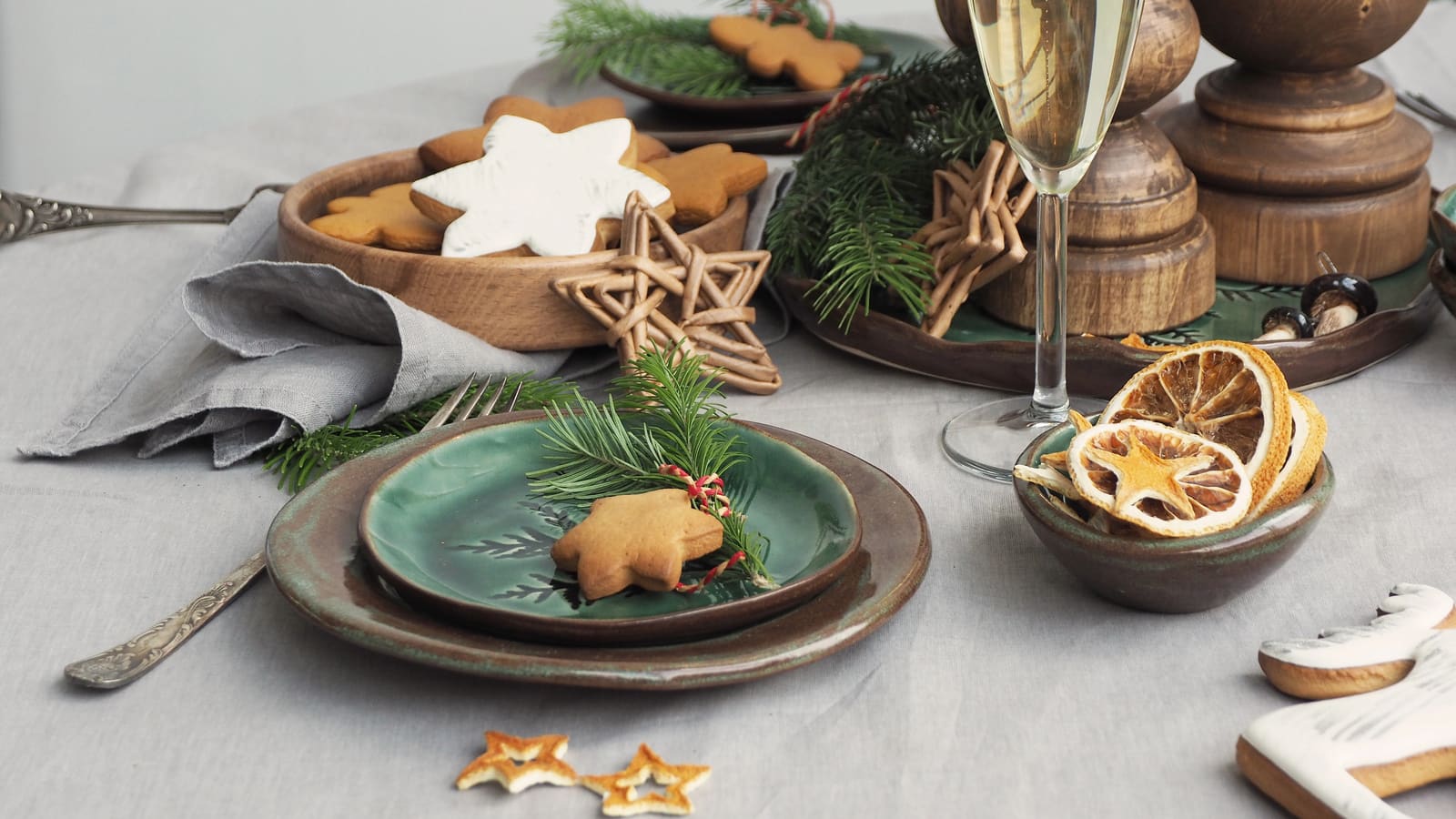 A festive table with gingerbread stars, dried orange slices and green plates