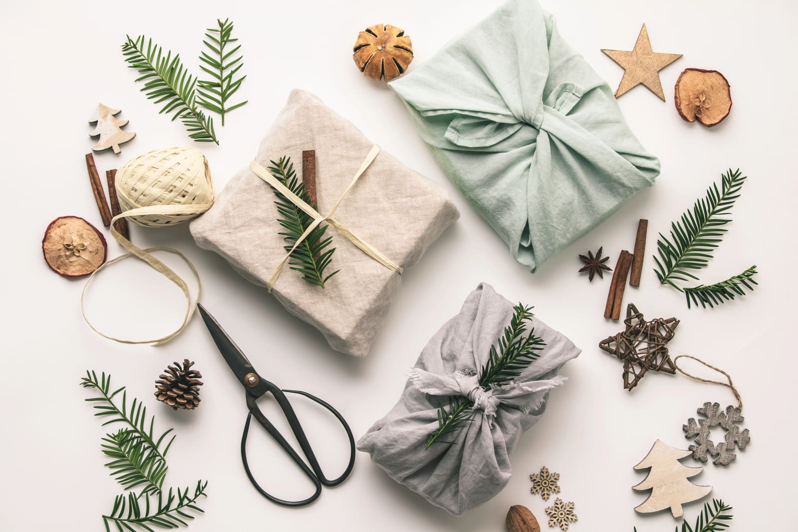 Gifts wrapped in linen and cotton cloth with fir sprigs, scissors and twine
