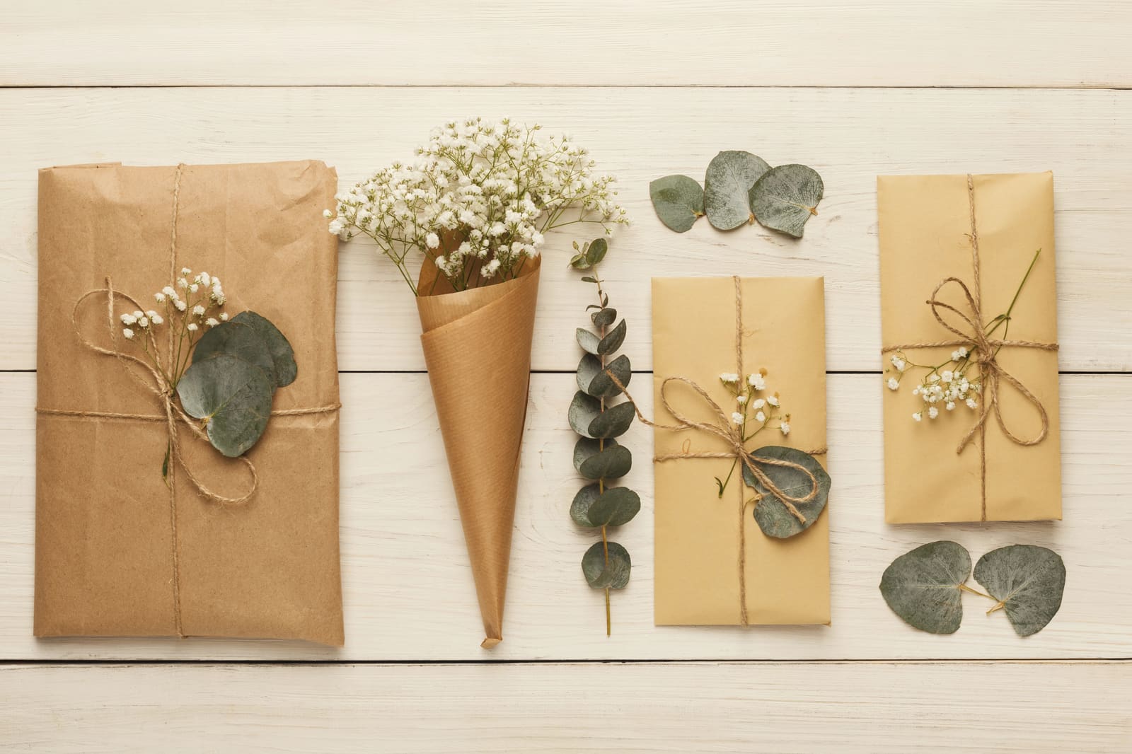 Kraft paper parcels tied with twine, small white flowers and eucalyptus leaves