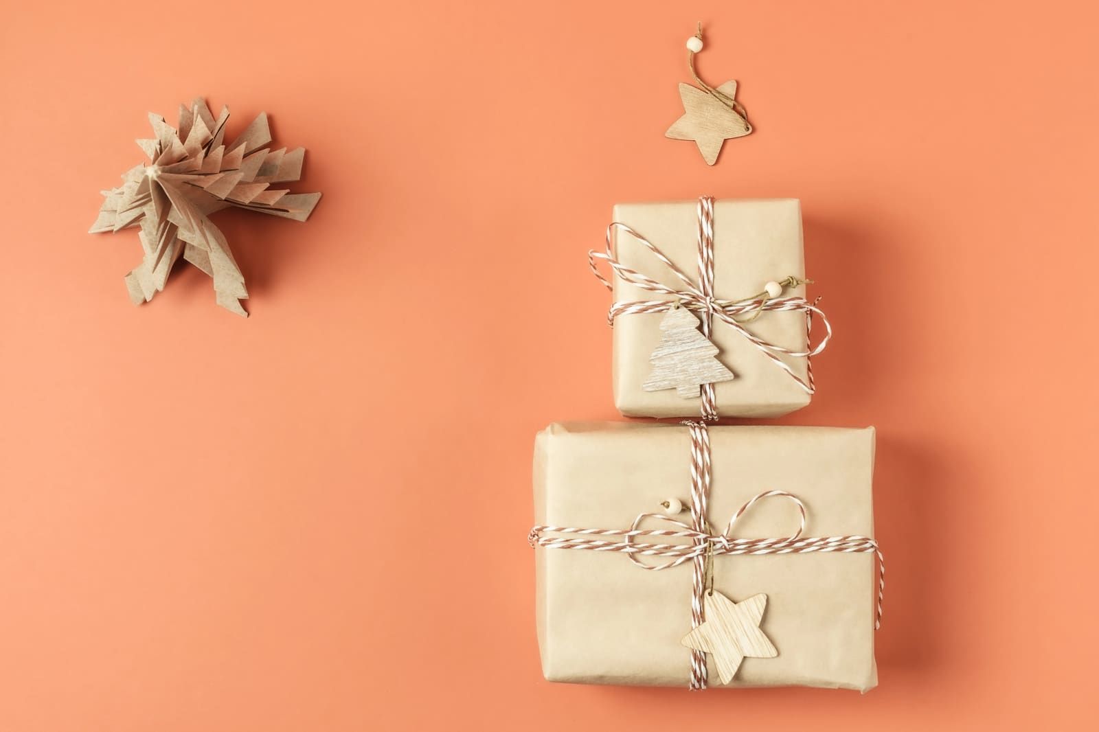 Two kraft parcels tied with striped twine and wooden star tags on coral