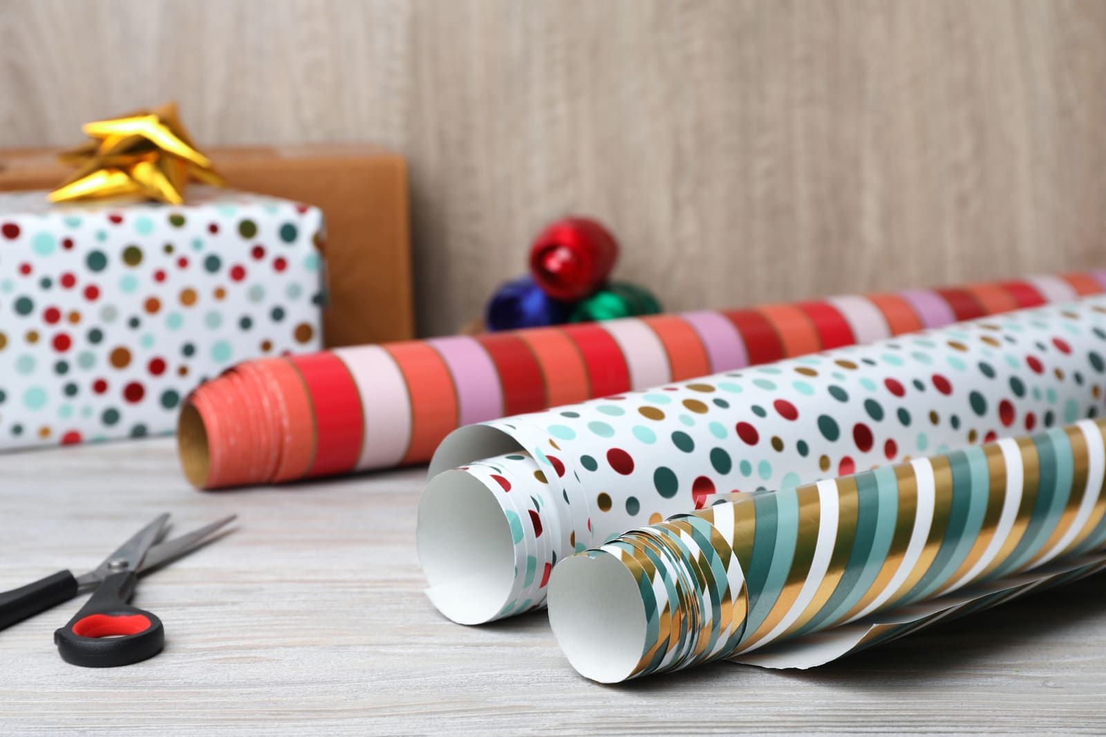Rolls of dotted and striped wrapping paper with scissors on a table