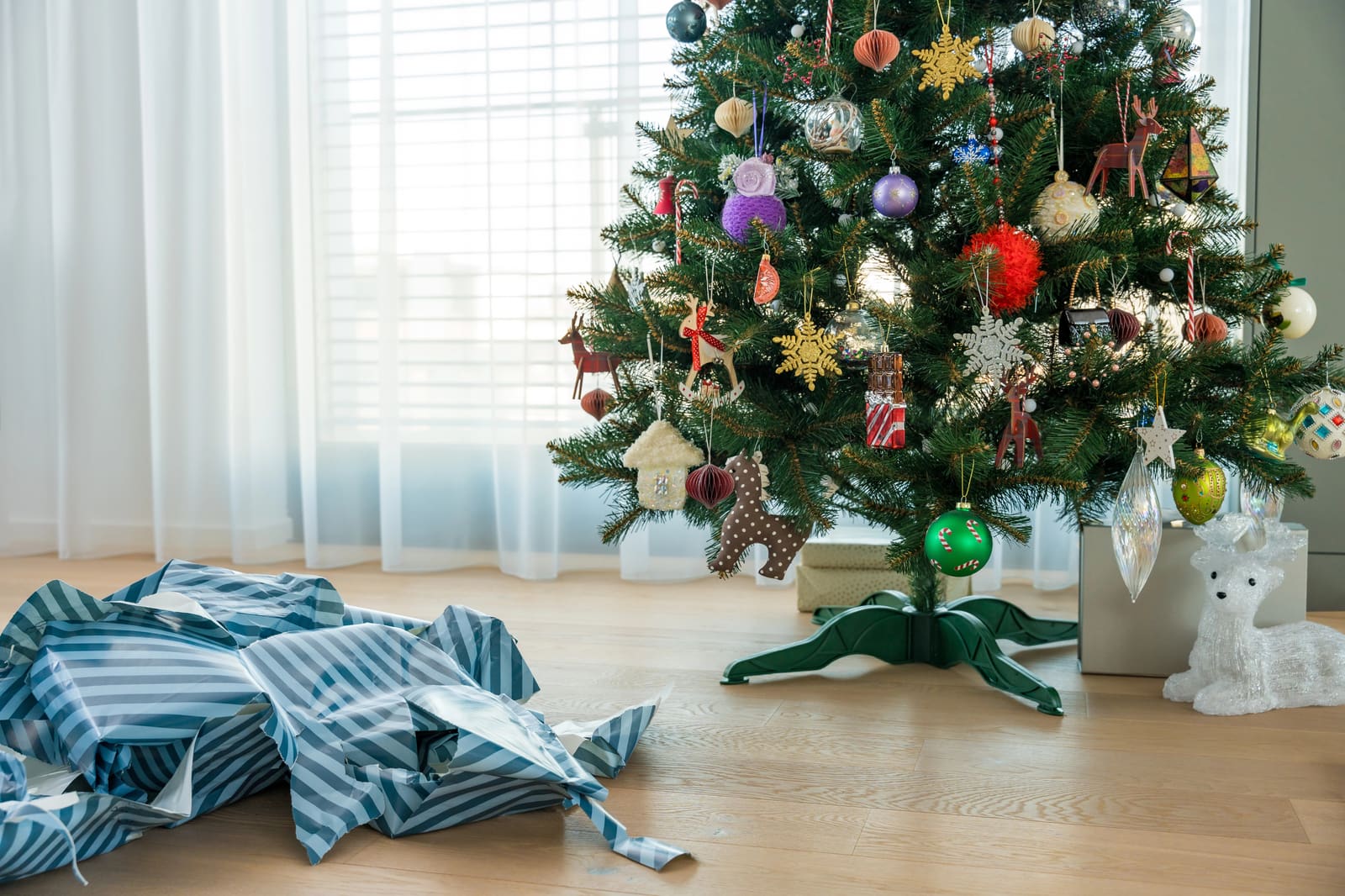 Torn striped wrapping paper on the floor beside a decorated Christmas tree