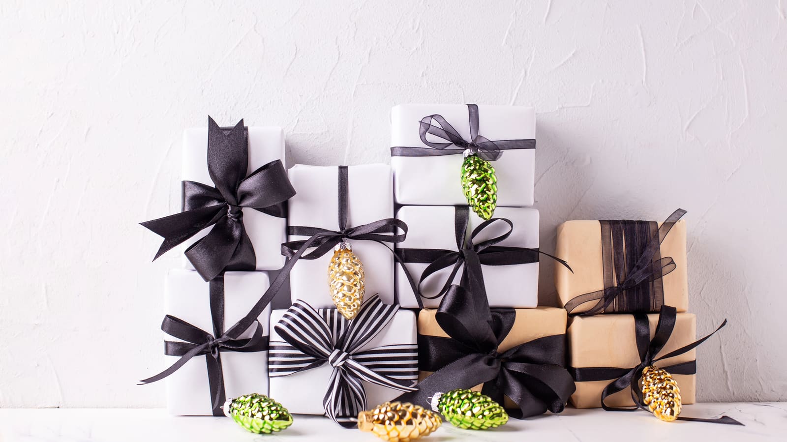A stack of white and kraft gifts tied with black ribbon bows