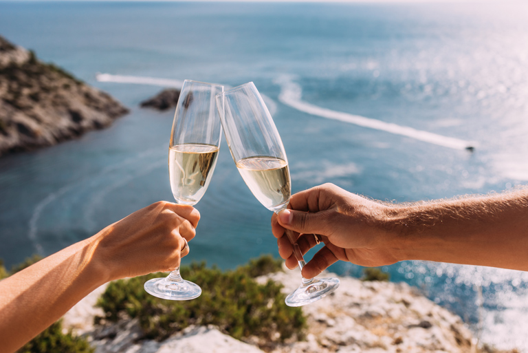 Two Champange flutes cheering in front a scenic background.