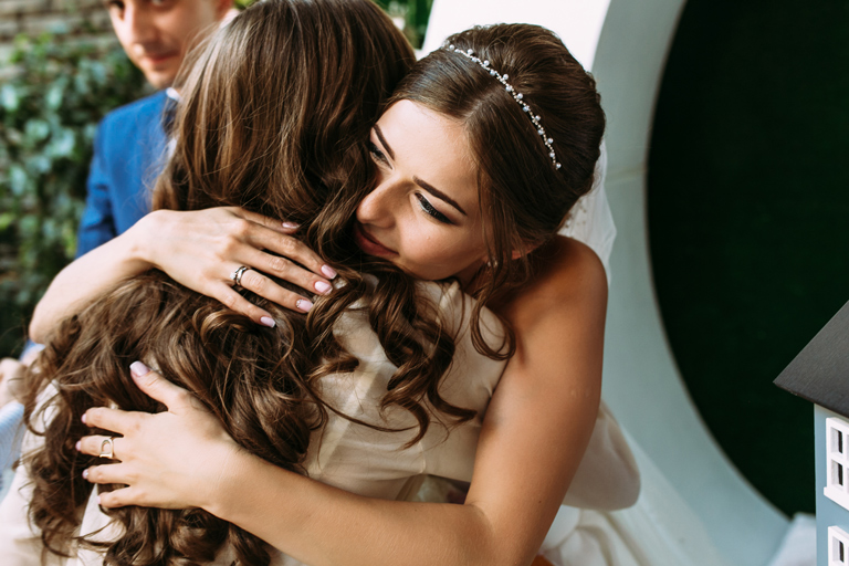 Bride being embraced by a friend at her wedding.