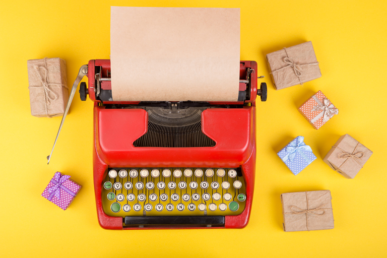 Typewriter with several gifts placed close to it.