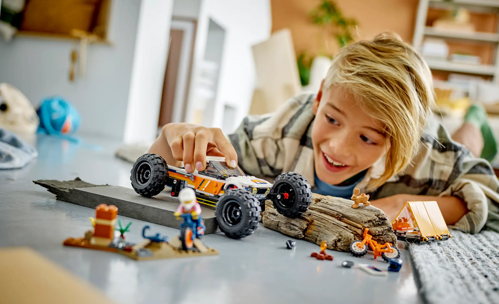 Bambino che gioca con un buggy fuoristrada LEGO Technic e allestimento di scena desertica